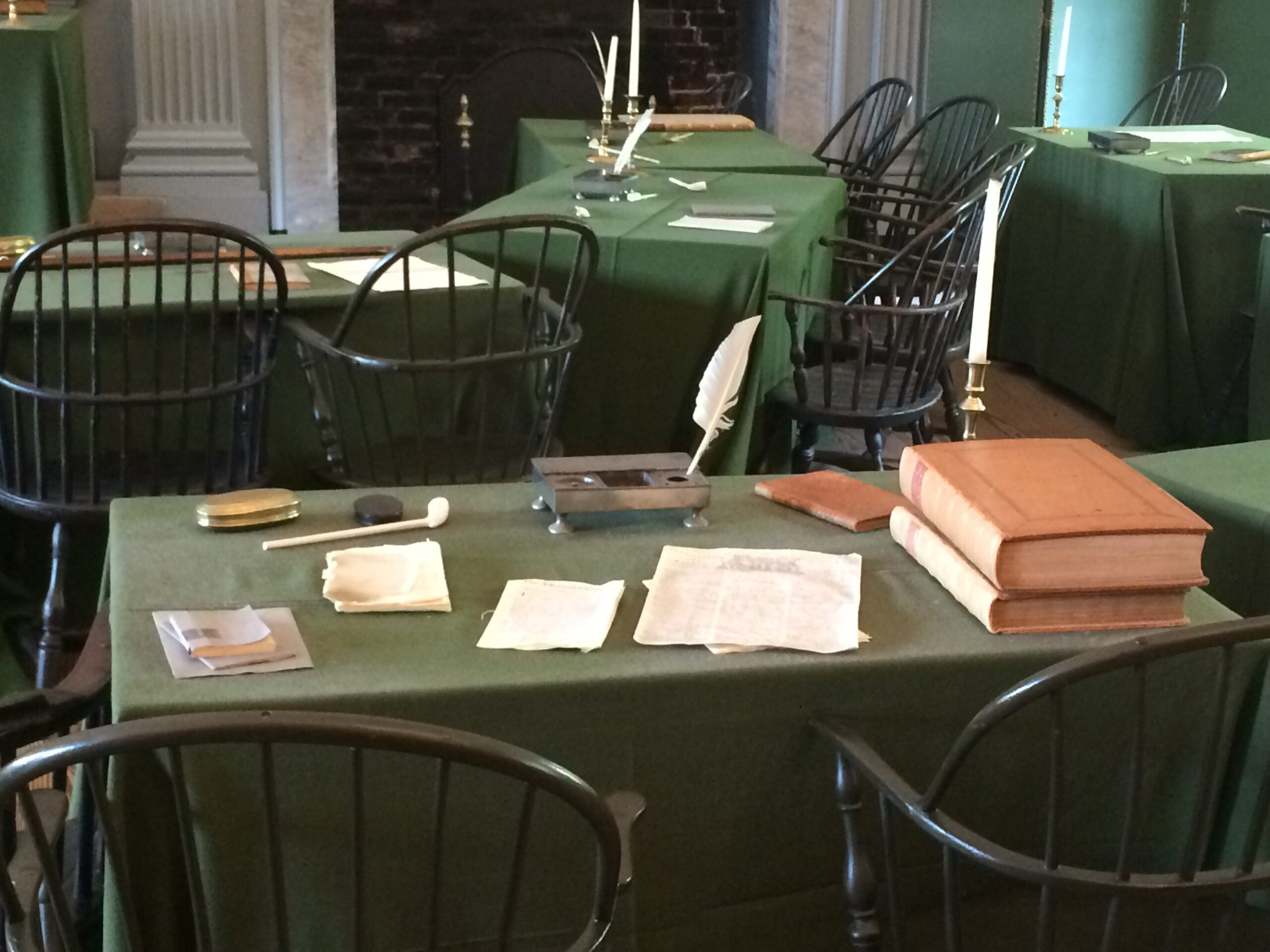 Table covered in green felt with books and quill pen.