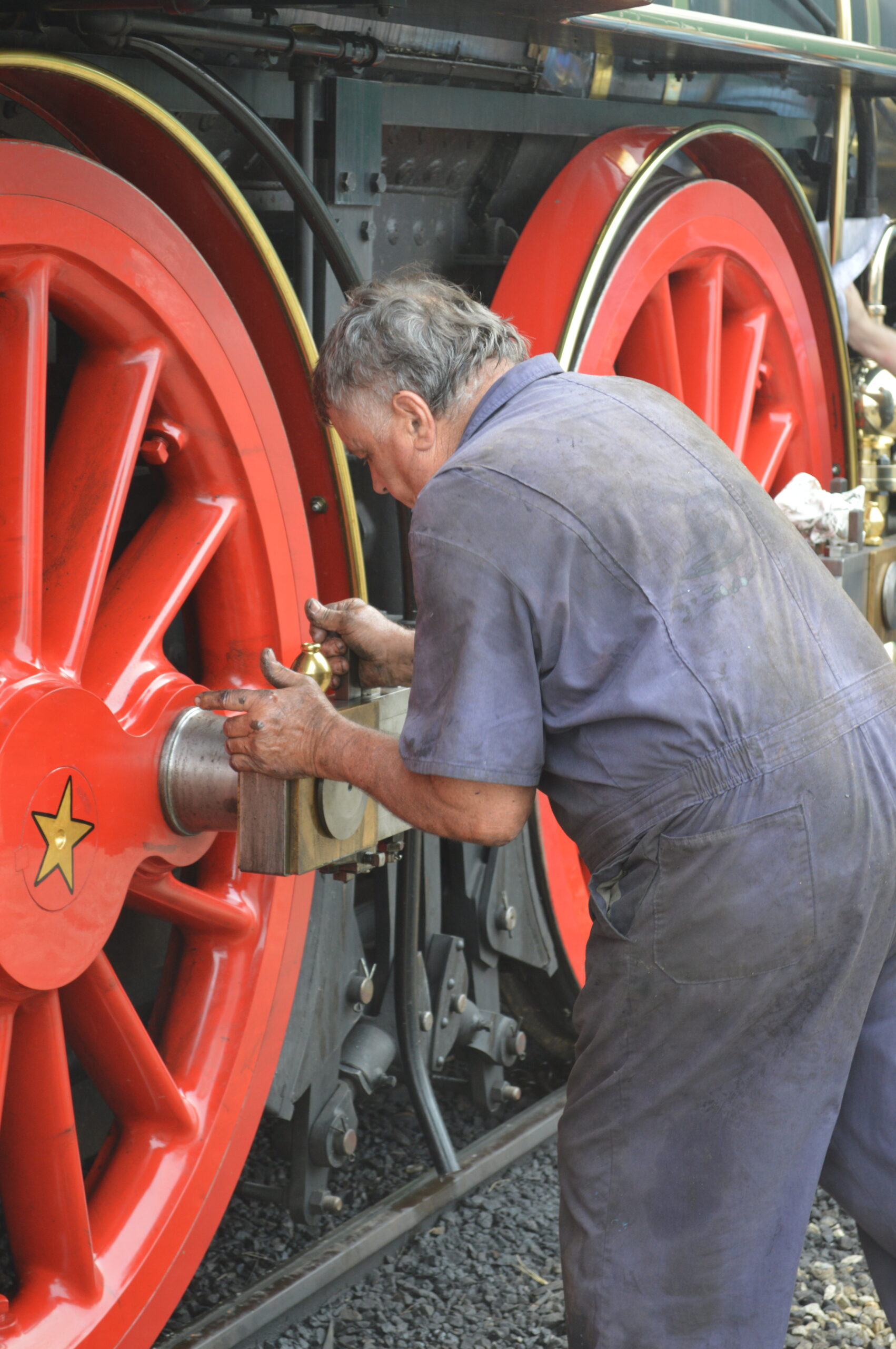 Man in coveralls works on a steam locomotive