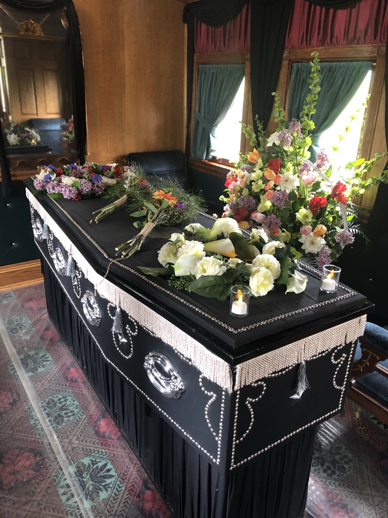 color photograph depicting a replica of Abraham Lincoln's coffin covered with flowers